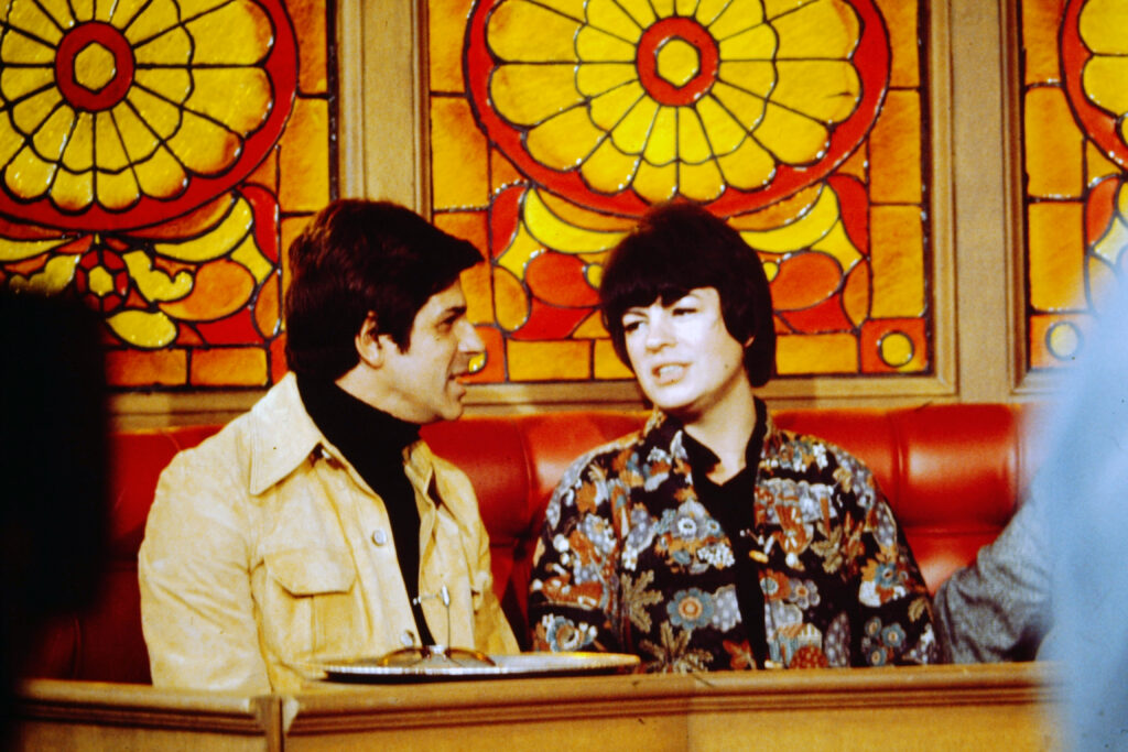 Dick Gautier and Jo Anne Worley on set, with painted glass windows behind